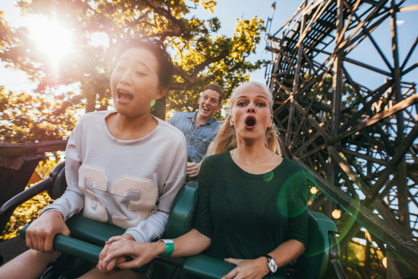 Fotografie cu prieteni tineri care se bucură de echitație pe roller coaster în parcul de distracții.