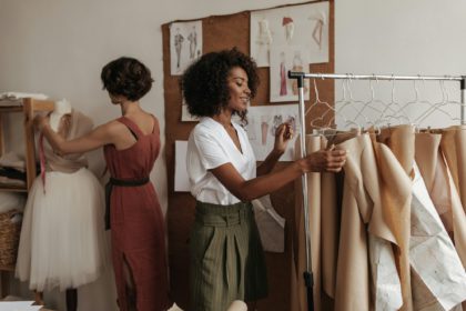 Dark-skinned and short-haired women in stylish summer outfits smile and pose in office of fashion d