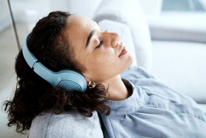 Face, woman and headphones for listening to music for calm, peace and mindfulness on home couch. Yo