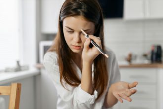 woman with eyebrow pencil sitting at the table in the kitchen cosmetics beauty care